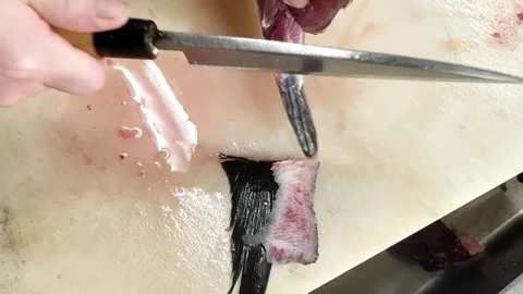 Knife slicing the collar meat of a fresh bluefin tuna held by hand, close up Stock Footage 339312834