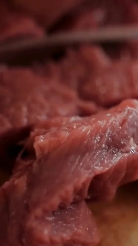 Knife slicing raw red meat on wooden cutting board Video stock 334183753