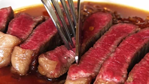 A knife slicing through a medium rare steak. Stock Footage 310947035