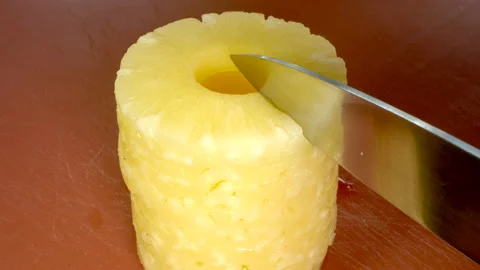 Knife starting to cut rings of pineapple into smaller pieces. Vidéo 200878848