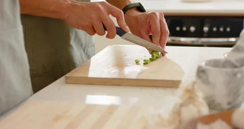 Knife tip is touching green vegetable, cutter is slicing rounds on wooden board Vidéo 343367150
