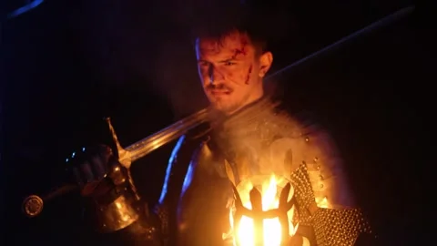 Knight in full armor holding a sword and a torch, stands in a dark night forest Stock Footage 330402000