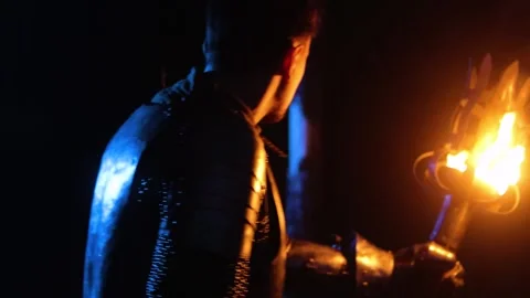 A knight in full armor, holding a sword and torch, walks through Stock Footage 331003729