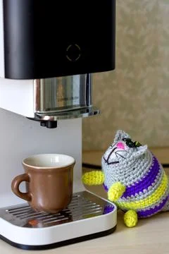 A knitted cat stands on a coffee machine. Stock Photos