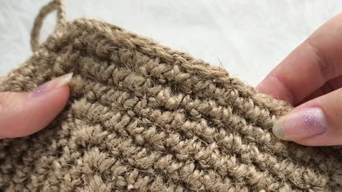 Knitted circle made of linen thread in a womans hand close-up. Knitted textile Stock Footage 316037855