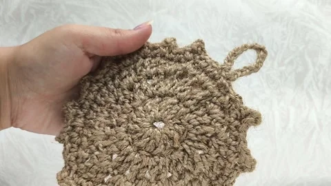 Knitted circle made of linen thread in a womans hand close-up. Knitted textile Stock Footage 316038074