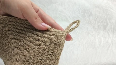 Knitted circle made of linen thread in a womans hand close-up. Knitted textile Stock Footage 316038234