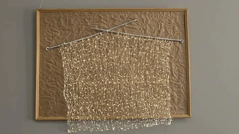 Knitted fabric with needles made from glowing golden LED garland, art object in Stock Footage 334571819