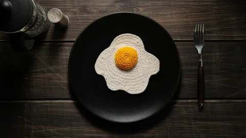 Knitted fried eggs shaking in a plate. Synthetic food. Top View Stock Footage 140626698