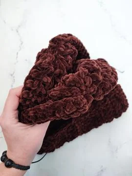 Knitted hat in hand, dark brown chocolate beanie hat, headwear Stock Photos