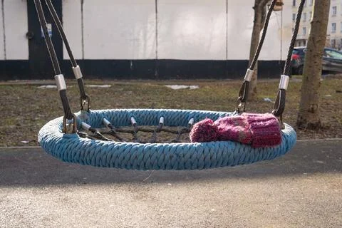 Knitted hat left on an empty rope swing in a playground Stock Photos