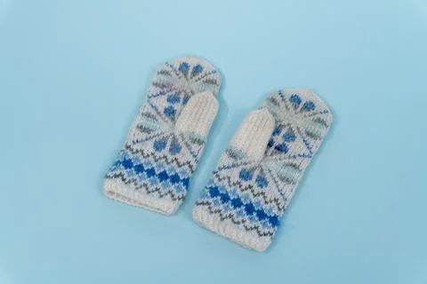 Knitted mittens with a snowflake pattern on a light blue background Stock Photos