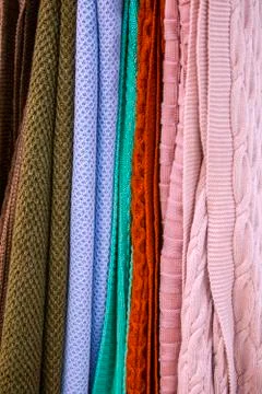 Knitted multi-colored plaids, blankets, knitted fabric textures in the store. Stock Photos