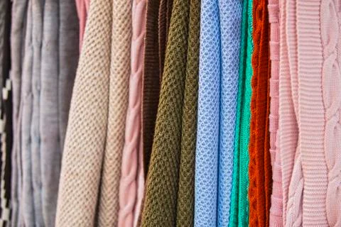 Knitted multi-colored plaids, blankets, knitted fabric textures in the store. Stock Photos