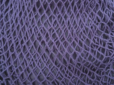 The knitted net background of one blue zero waste string bag. Selective focus. Stock Photos
