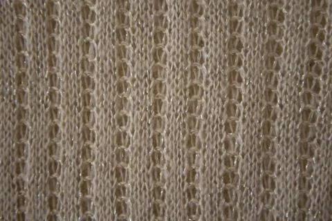 Knitted openwork pattern with gold and beige threads. Knitted background. Kni Stock Photos