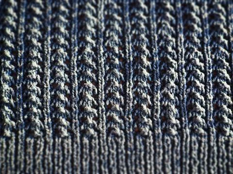 Knitted pattern of blue yarn. Lush machine or hand knitting. Warm wardrobe fo Stock Photos