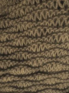 Knitted pattern of brown or beige yarn. Lush machine or hand knitting. Warm w Stock Photos