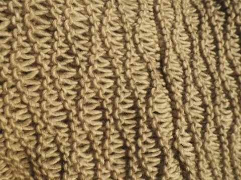 Knitted pattern of brown or beige yarn. Lush machine or hand knitting. Warm w Stock Photos