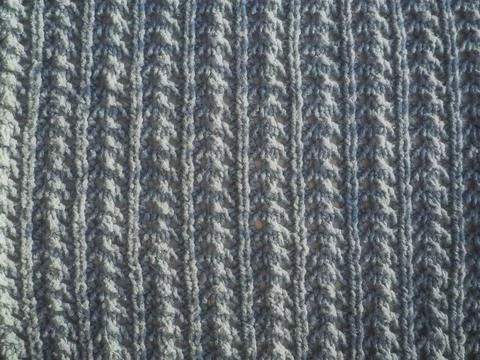 Knitted pattern of gray yarn. Lush machine or hand knitting. Warm wardrobe fo Stock Photos