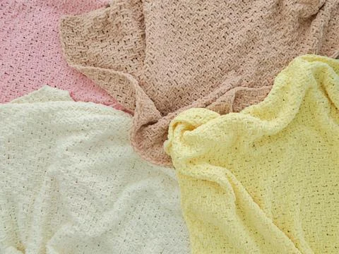 Knitted plaids of different colors. Background. Creases on soft surfaces. Stock Photos