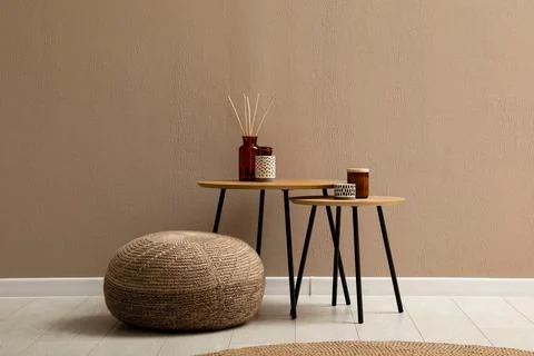 Knitted pouf and decor elements near beige wall indoors. Space for text Stock Photos