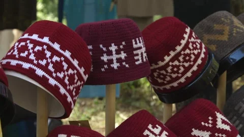 Knitted red and gray caps with folk patterns on display at the craft market Stock Footage 251846402