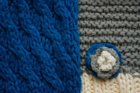 Knitted scarf pattern. Blue and gery threads. Small knitted flower on a scarf Stock Photos
