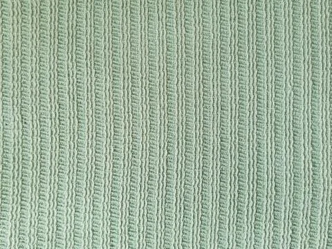 Knitted textile texture with a vertical pale green hue. Stock Photos