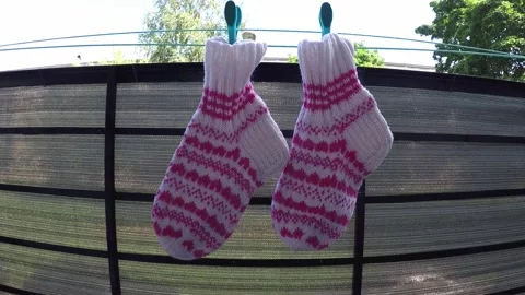 Knitted wool socks with abstract pattern hanging with clothespin on balcony Stock Footage 156612098