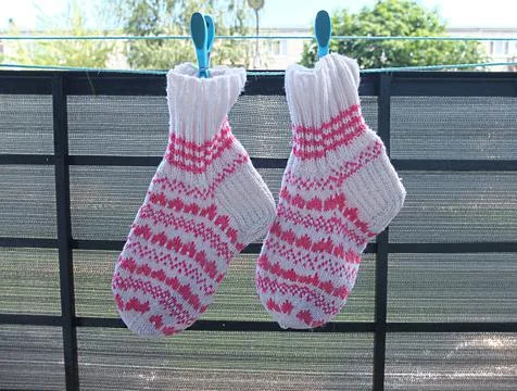 Knitted wool socks with abstract pattern hanging with clothespin on balcony Stock Photos