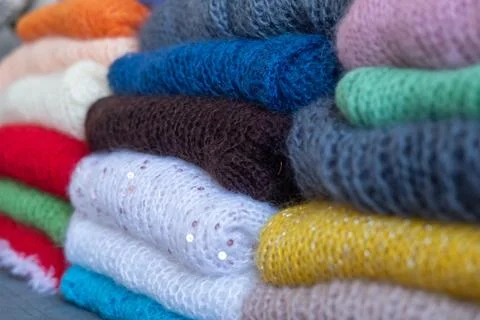 Knitted wool sweaters folded in stack, soft fuzzy texture. Stock Photos