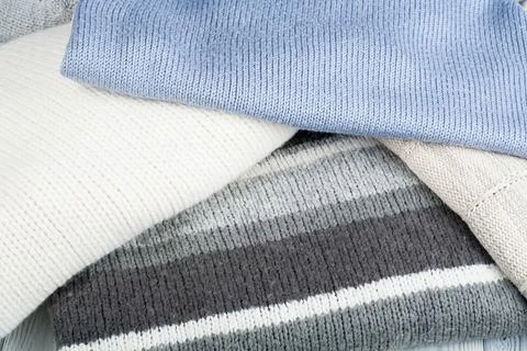 Knitted wool sweaters. Pile of knitted winter clothes on wooden background,.. Stock Photos