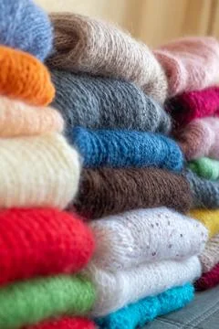 Knitted wool sweaters stacked high, colorful soft yarn fabric folded in piles Stock Photos