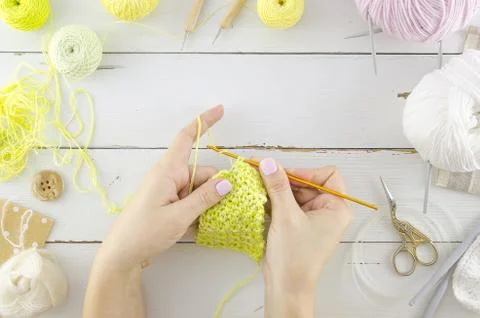 Knitting concept with woman's hands. Flat lay wooden desk with tools and Stock Photos