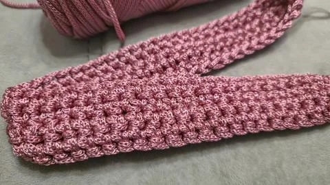 Knitting elements of a pink women's bag, hand knitting with a long handle. Stock Photos