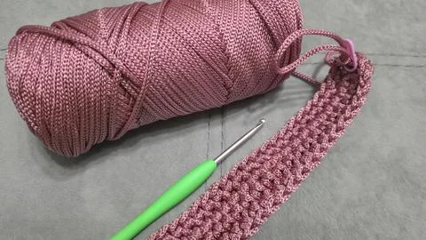 Knitting elements of a pink women's bag, hand knitting with a long handle. Stock Photos