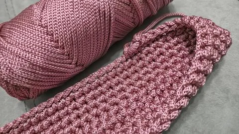 Knitting elements of a pink women's bag, hand knitting with a long handle. Stock Photos