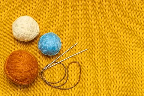 Knitting needles and wool threads on a knitted background. Stock Photos