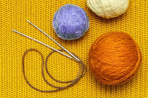 Knitting needles and wool threads on a knitted background Stock Photos
