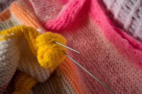 Knitting needles are inserted into a ball of yarn Stock Photos