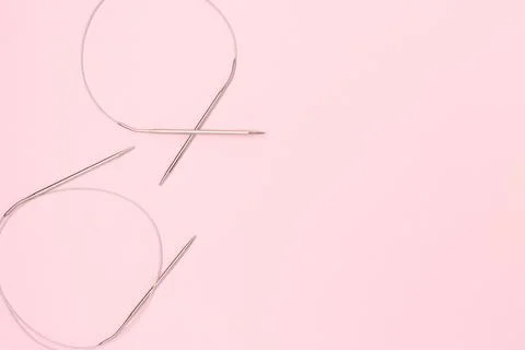 Knitting needles on a pink background. Stock Photos