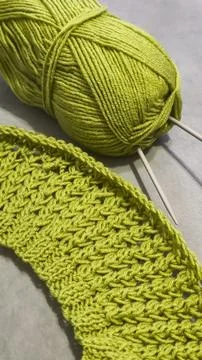 Knitting pattern using thick green yarn. Needles, thread, and green fabric Фото