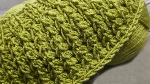 Knitting pattern using thick green yarn. Needles, thread, and green fabric Stock Photos
