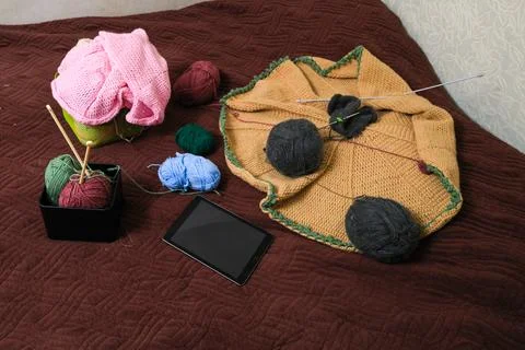 Knitting project in progress with yarn balls, needles, and tablet on a text.. Stock Photos