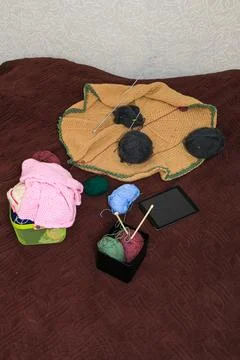 Knitting project in progress with yarn balls, needles, and tablet on a text.. Stock Photos