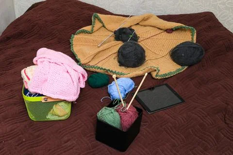Knitting project in progress with yarn, needles, and tablet on a textured b.. Stock Photos