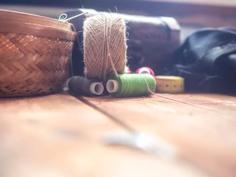 Knitting thread rolls near the box with other supplies on a wooden table Stock Photos