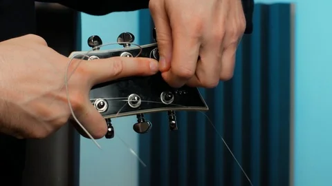 Knot and tighten a string on a guitar Stock Footage 95854741