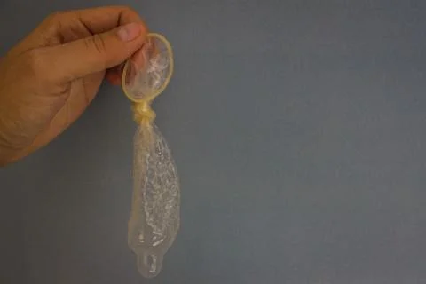 Knotted condom in hand. Stock Photos